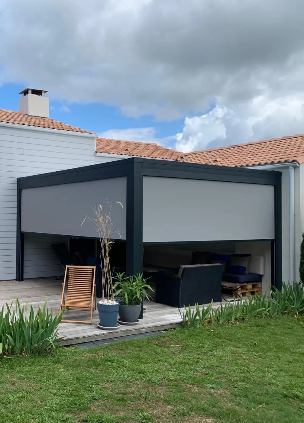 Pergola bioclimatique en aluminium anthracite équipée de stores verticaux, à lames orientables